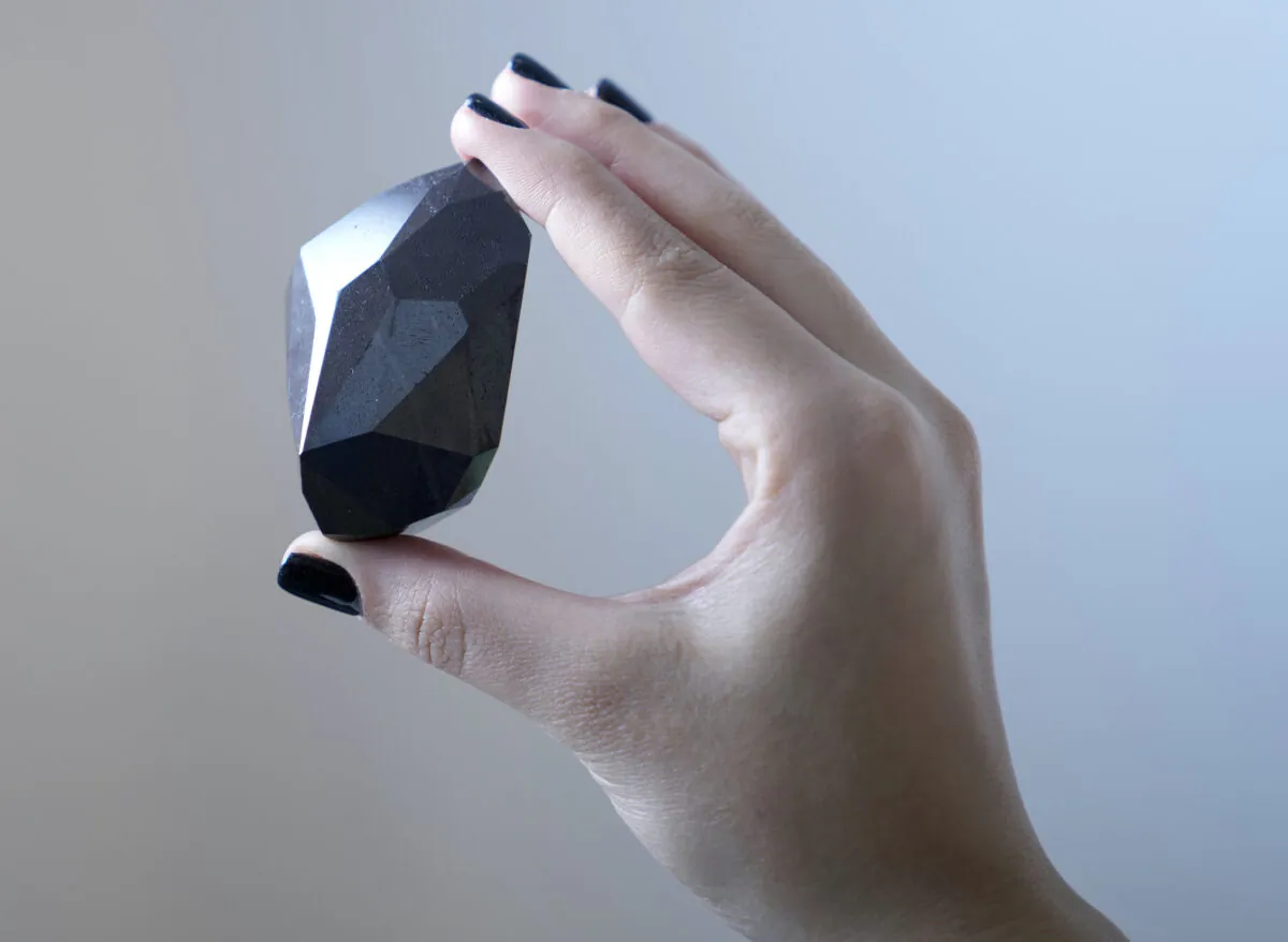 An employee of Sotheby's Dubai presents a 555.55 Carat Black Diamond “The Enigma” during the World Unveiling of Major auction highlight at Sotheby's Dubai gallery, in Dubai, United Arab Emirates, on Jan. 17, 2022. (Kamran Jebreili/AP Photo)