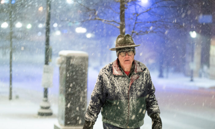 A man walks along Main St. as snow falls on Jan. 16, 2022, in Greenville, S.C. (Sean Rayford/Getty Images)