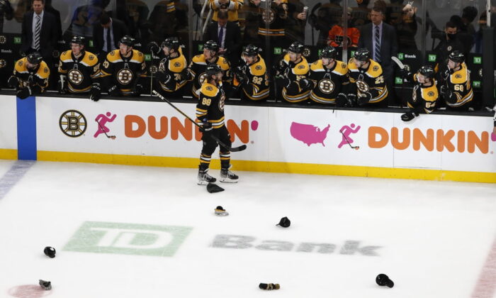 Hats litter the ice as Boston Bruins right wing David Pastrnak (88) is congratulated by teammates after scoring his third goal of the game against the Philadelphia Flyers during the second period at TD Garden in  Boston on Jan 13, 2022. (Winslow Townson/USA TODAY Sports via Field Level Media)