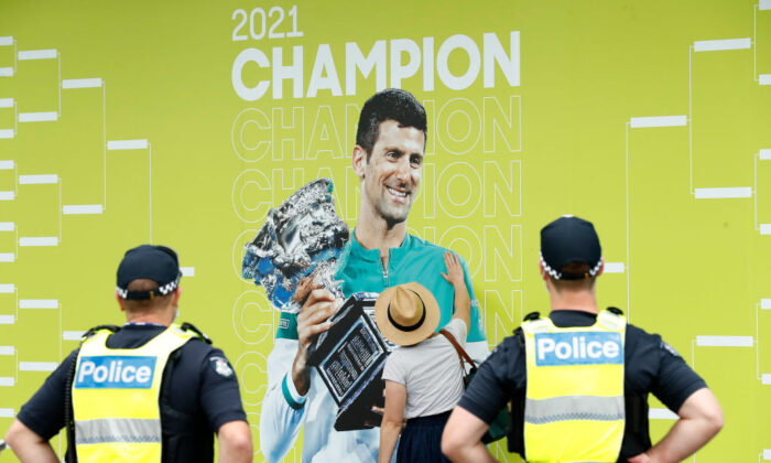 A spectator touches a banner of 2021 Men's Australian Open winner Novak Djokovic of Serbia as police officers look on during day one of the 2022 Australian Open at Melbourne Park in Melbourne, Australia, on Jan. 17, 2022. (Darrian Traynor/Getty Images)