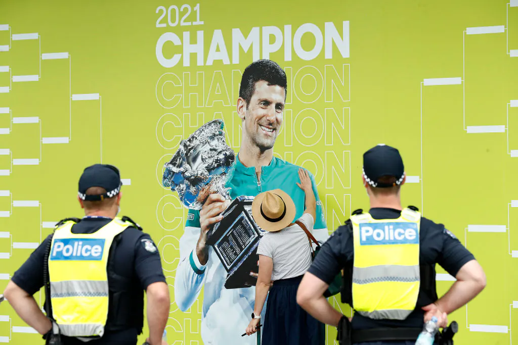 A spectator touches a banner of 2021 Men's Australian Open winner Novak Djokovic of Serbia as police officers look on during day one of the 2022 Australian Open at Melbourne Park in Melbourne, Australia, on Jan. 17, 2022. (Darrian Traynor/Getty Images)