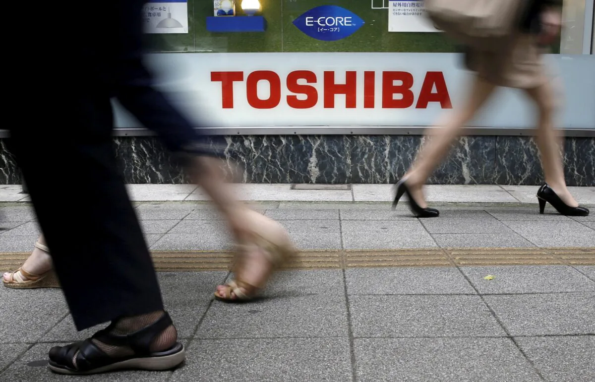Pedestrians walk past a logo of Toshiba Corp. outside an electronics retailer in Tokyo, on Sept. 14, 2015. (Toru Hanai/Reuters)