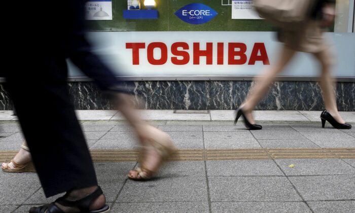 Pedestrians passing the Toshiba logo outside a consumer electronics retail store in Tokyo on September 14, 2015.  (Toru Hanai / Reuters)