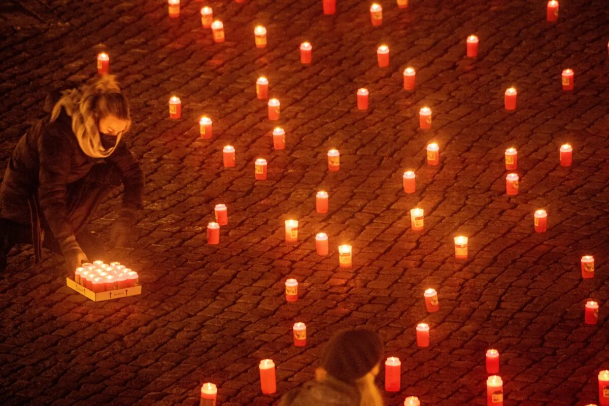 People light about 1,500 candles in memory of those who have died from coronavirus and COVID-19 disease infection at the market place in Greifswald, Germany, on Jan. 17, 2022. (Stefan Sauer/DPA via AP)