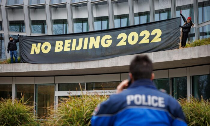 A policeman talks on the phone as Tibetan activists from the Students for a Free Tibet association hang a banner during a protest in front of the International Olympic Committee (IOC) headquarters ahead of February's Beijing 2022 Winter Olympics, in Lausanne, on Dec. 11, 2021. (Valentin Flauraud/AFP via Getty Images)