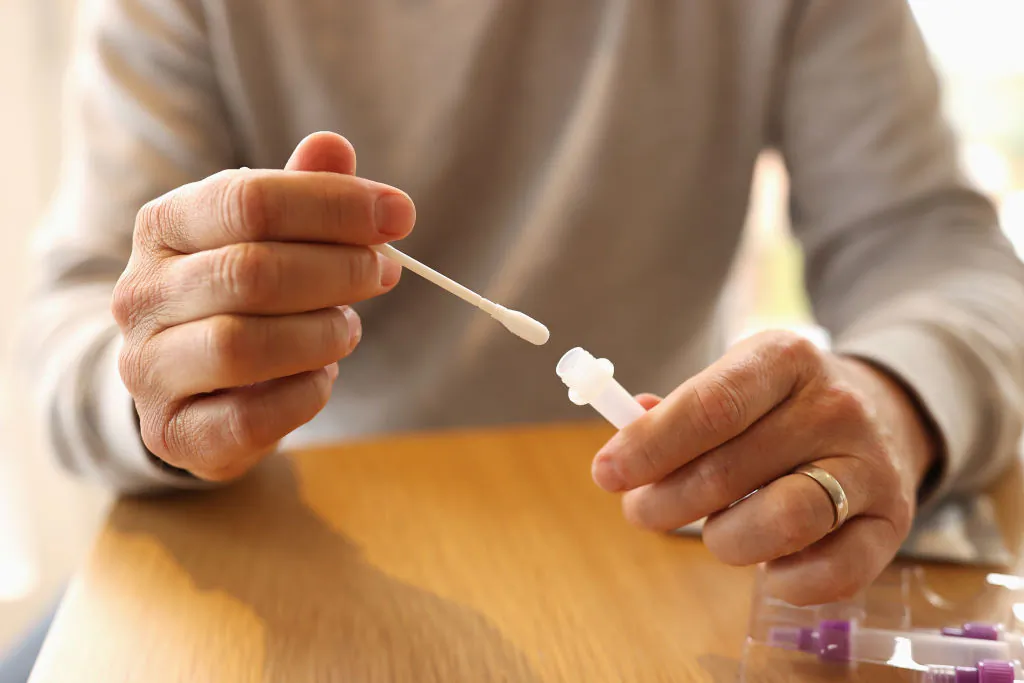 In this photo illustration a man uses a COVID-19 rapid antigen test kit at home in Sydney, Australia, on Sept. 29, 2021. (Cameron Spencer/Getty Images)
