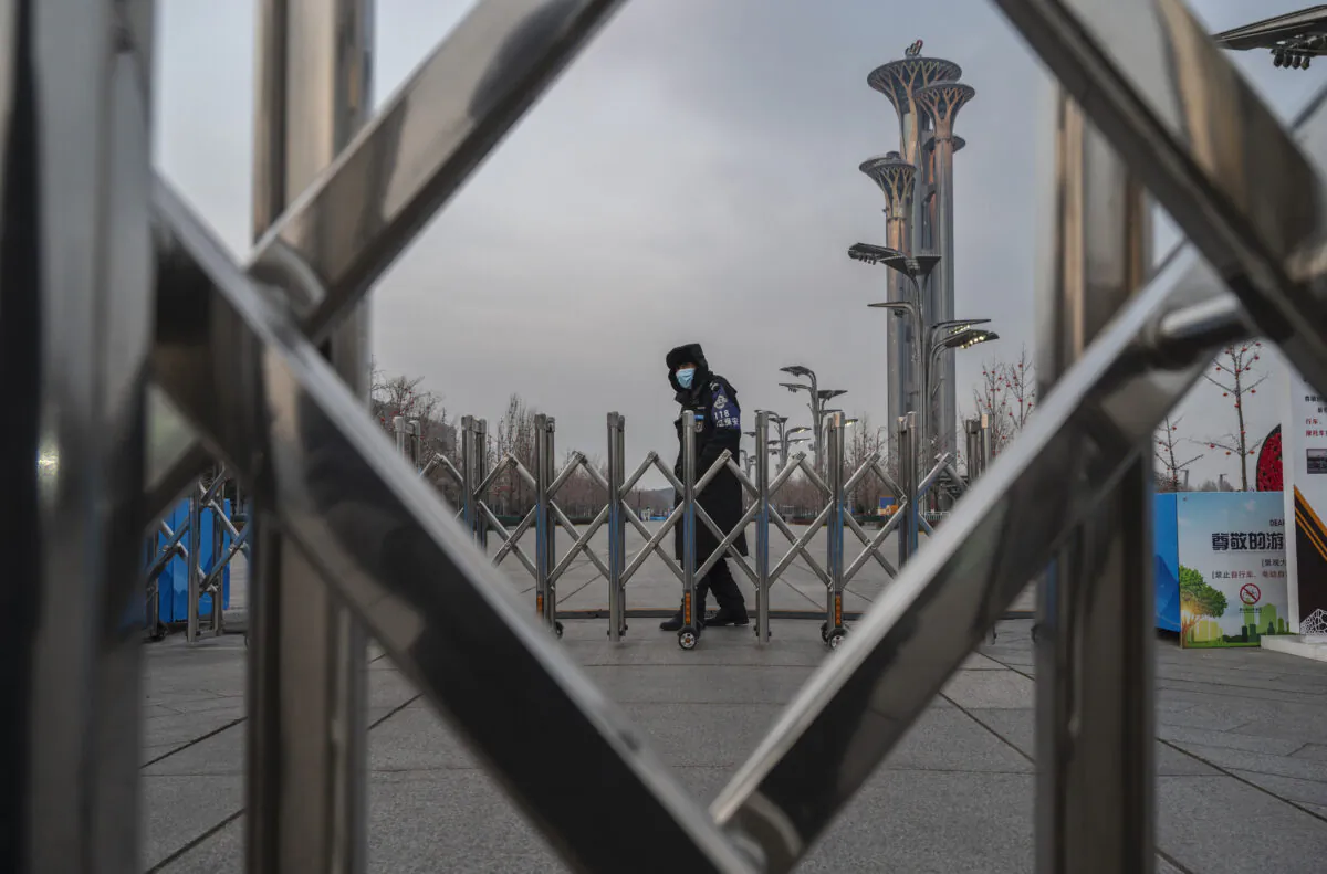 A security guard stands behind a barrier outside the National Stadium, also known as the Bird's Nest, that will be part of the closed loop "bubble" for visitors and locals taking part in the Beijing 2022 Winter Olympics and Paralympics, in front of the Olympic Tower at the Olympic Park in Beijing, China, on Jan. 19, 2022. (Kevin Frayer/Getty Images)