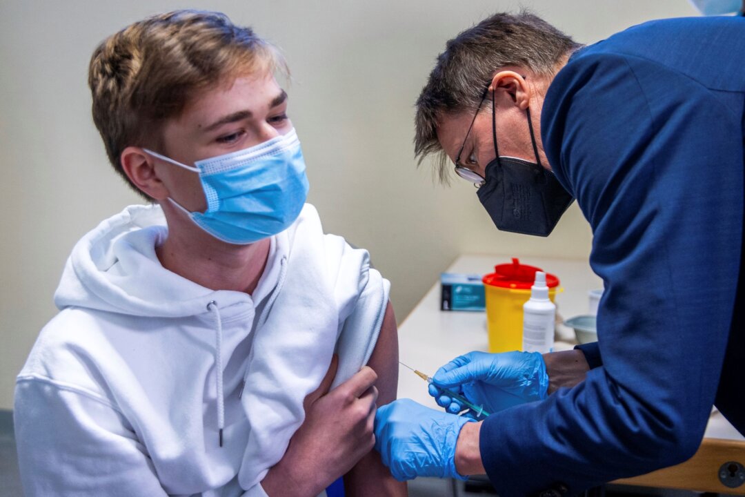 German Minister of Health Karl Lauterbach, right, administers an injection with the Pfizer vaccine to man at a vaccination center in the Sports and Congress Hall in Schwerin, Germany, on Jan. 17, 2022. (Jens Buettner/Pool via AP)