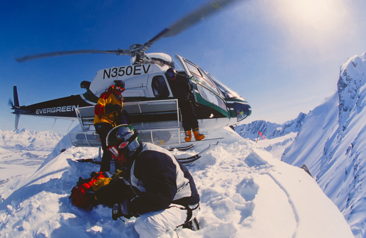 Snowboarder Esben Pedersen being dropped of by helicopter on an isolated peak in the Chugach Mountains on April, 22, 2002. Valdez is the hub for Heli-skiing in Alaska. (OutdoorWorks/Shutterstock)