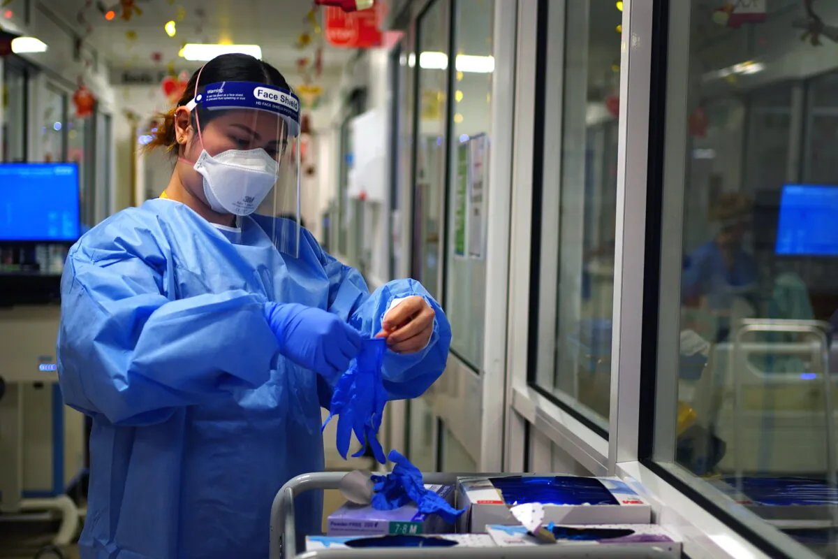 A nurse puts on PPE in a ward for COVID-19 patients at King's College Hospital in south east London on Dec. 21, 2021. (Victoria Jones/PA)