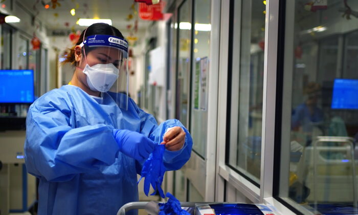 A nurse puts on PPE in a ward for COVID-19 patients at King's College Hospital in south east London on Dec. 21, 2021. (Victoria Jones/PA)