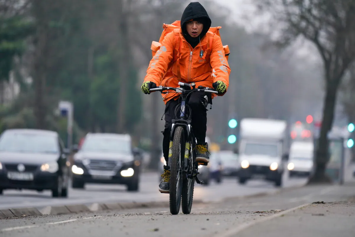 A woman rides a bicycle adjacent to heavy traffic in Birmingham, England on Jan. 25, 2022. (Jacob King/PA)