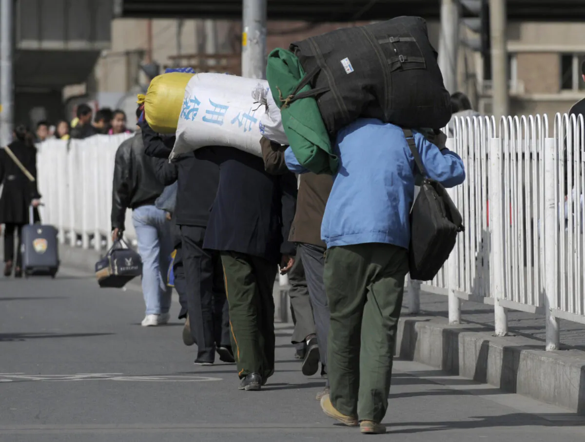 Migrant workers carrying their luggage through a street in Beijing on March 25, 2009. (Liu Jin/AFP via Getty Images)