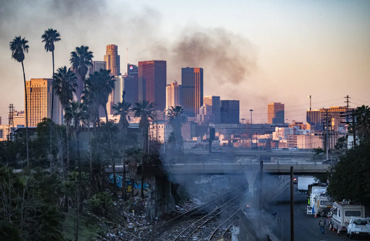 A fire burns in a homeless encampment while shredded boxes cover railroad tracks after ongoing theft in Los Angeles, Calif., on Jan. 20, 2022. (John Fredricks/The Epoch Times)