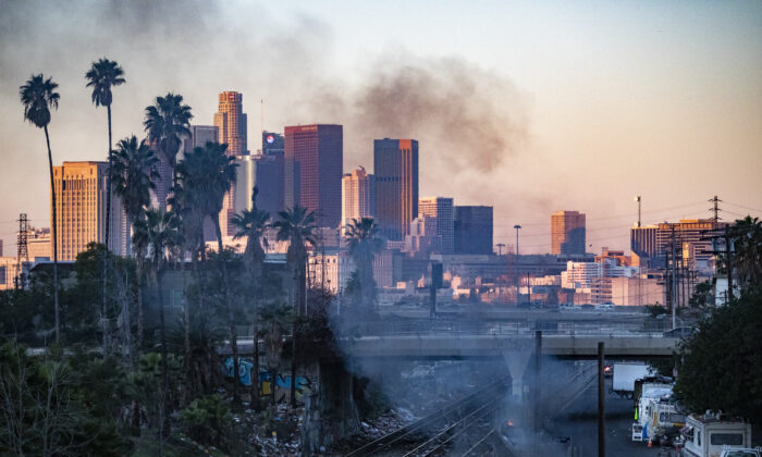 A fire burns in a homeless encampment while shredded boxes cover railroad tracks after ongoing theft in Los Angeles, Calif., on Jan. 20, 2022. (John Fredricks/The Epoch Times)