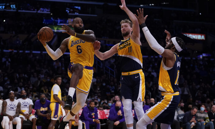 Los Angeles Lakers forward LeBron James (6) passes against Indiana Pacers forward Domantas Sabonis (11) and forward Oshae Brissett (12) during the first half of an NBA basketball game in Los Angeles on Jan. 19, 2022. (Ashley Landis/AP Photo)