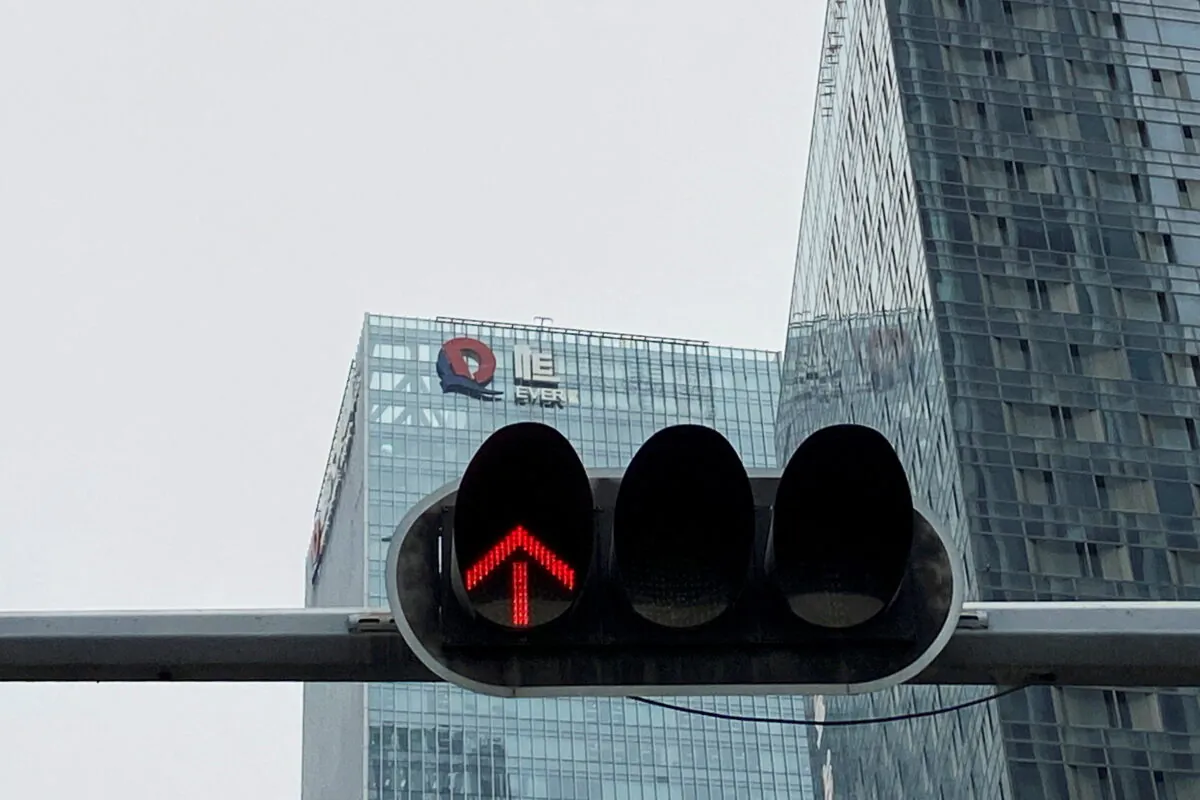A partially removed company logo of China Evergrande Group is seen on the facade of its headquarters, near a traffic light in Shenzhen, Guangdong Province, China on Jan. 10, 2022. (David Kirton/Reuters)