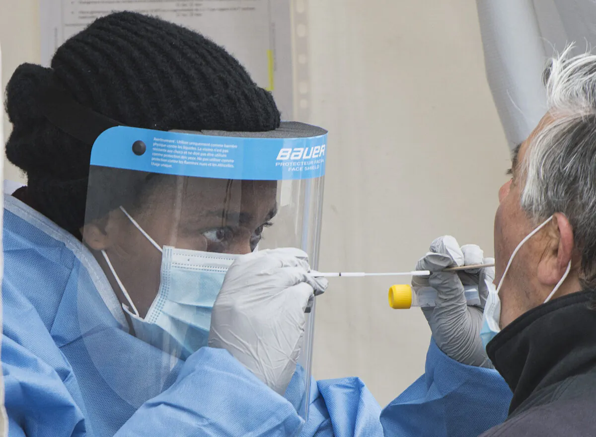 A health-care worker prepares to swab a man at a walk-in COVID-19 test clinic in Montreal North on May 10, 2020. (The Canadian Press/Graham Hughes)