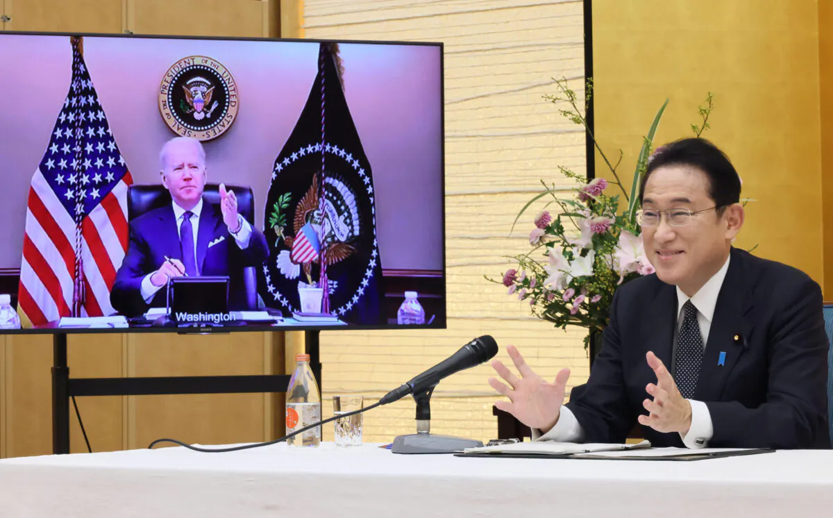 Japanese Prime Minister Fumio Kishida (R) talks in a virtual meeting with U.S. President Joe Biden, shown in the monitor, in a room of the prime minister's official residence in Tokyo, on Jan. 21, 2022. (Cabinet Secretariat/Kyodo News via AP)