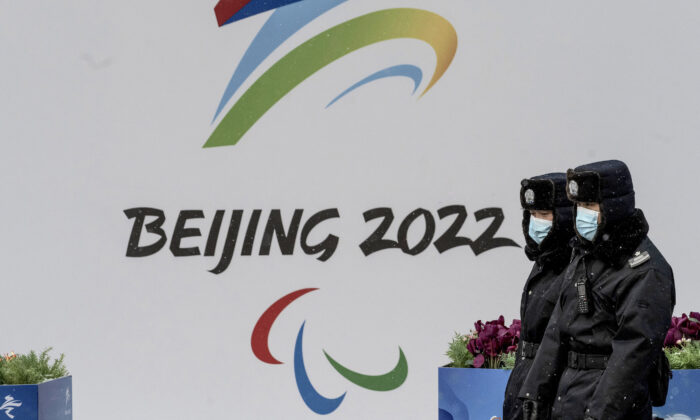 Chinese security guards walk by a billboard for the 2022 Winter Olympics in Beijing on Jan. 20, 2022. (Kevin Frayer/Getty Images)