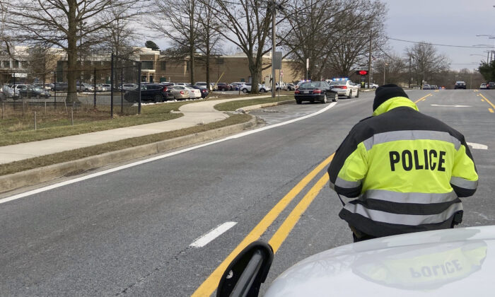 A policeman stands near the scene at Col. Zadok Magruder High School where authorities say a student was shot and a suspect was in custody, in Rockville, Md., on Jan. 21, 2022. (Freddy Kunkle/The Washington Post via AP)