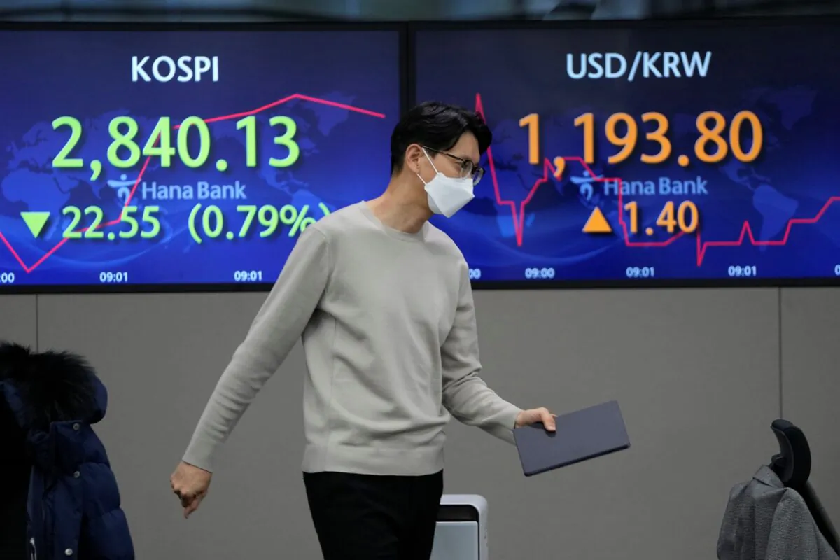 A currency trader walks by the screens showing the Korea Composite Stock Price Index (KOSPI) (L), and the foreign exchange rate between U.S. dollar and South Korean won at a foreign exchange dealing room in Seoul, South Korea, on Jan. 21, 2022. (Lee Jin-man/AP Photo)