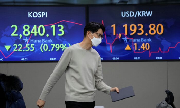 A currency trader walks by the screens showing the Korea Composite Stock Price Index (KOSPI) (L), and the foreign exchange rate between U.S. dollar and South Korean won at a foreign exchange dealing room in Seoul, South Korea, on Jan. 21, 2022. (Lee Jin-man/AP Photo)