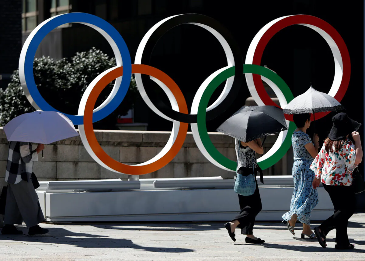 Passersby holding sunshades walk past Olympic rings displayed at Nihonbashi district in Tokyo, on Aug. 5, 2019. (Issei Kato/Reuters)