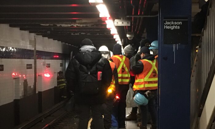 MTA teams and onlookers at the scene of a crash where a man jumped in front of a train, at the Jackson Heights-Roosevelt Ave subway station in New York, early on Jan. 22, 2022. (The Epoch Times)