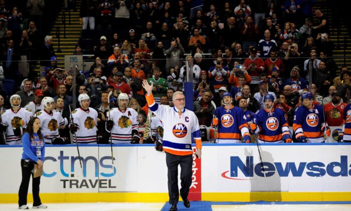 Former New York Islander Clark Gillies waves to fans before he dropped a ceremonial puck before the Islanders' NHL hockey game against the Chicago Blackhawks at Nassau Coliseum in Uniondale, New York, on Dec. 13, 2014.  (Kathy Kmonicek/AP Photo)