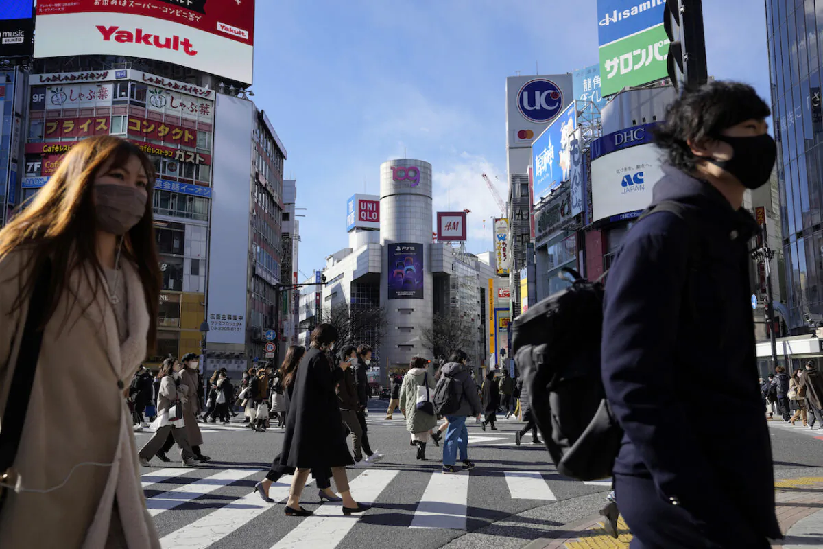 People walk along a pedestrian crossing in Tokyo, on Jan. 21, 2022. (AP Photo/Eugene Hoshiko)