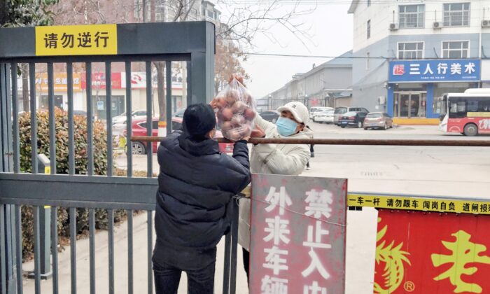 A resident receives food at the entrance of a residental area closed off and restricted due to an outbreak of the Covid-19 coronavirus in Anyang in China's central Henan province on January 12, 2022. - China OUT (Photo by AFP) / China OUT (Photo by STR/AFP via Getty Images)