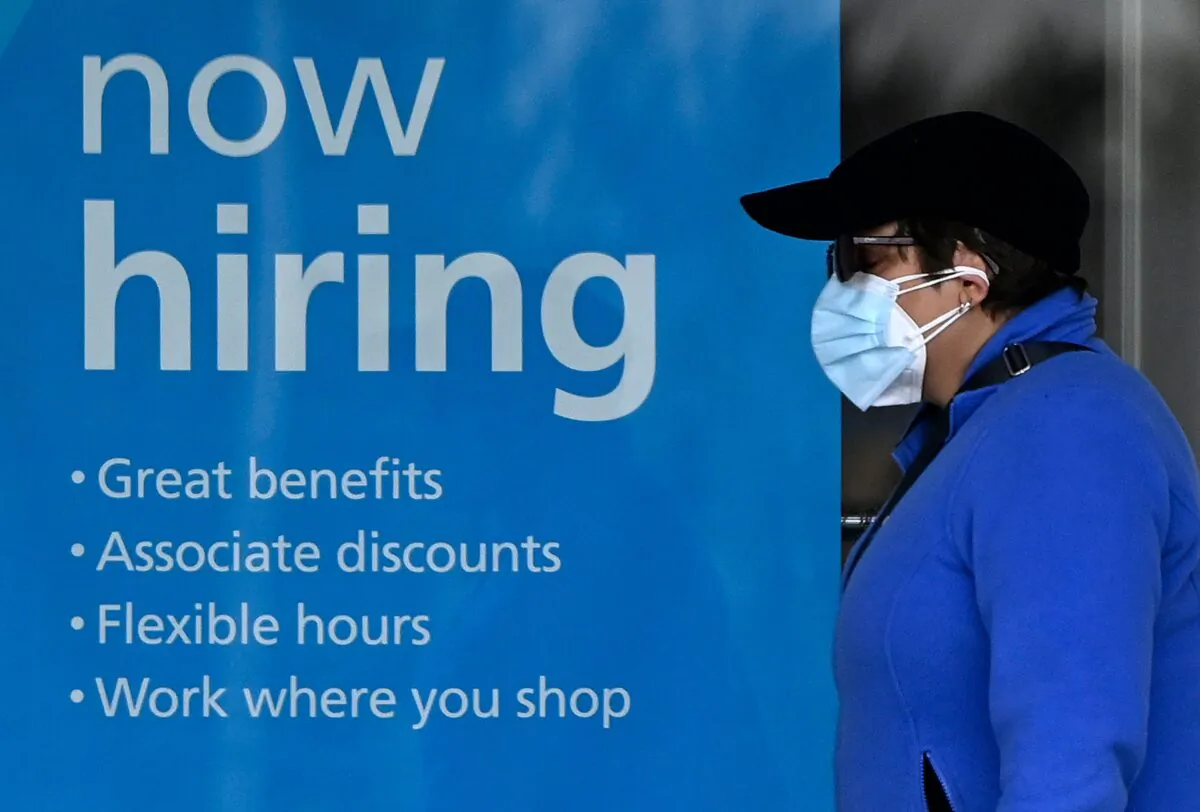 A woman walks past a “now hiring” sign in front of a store in Arlington, Virginia, on Jan. 13, 2022. (Olivier Douliery/AFP via Getty Images)