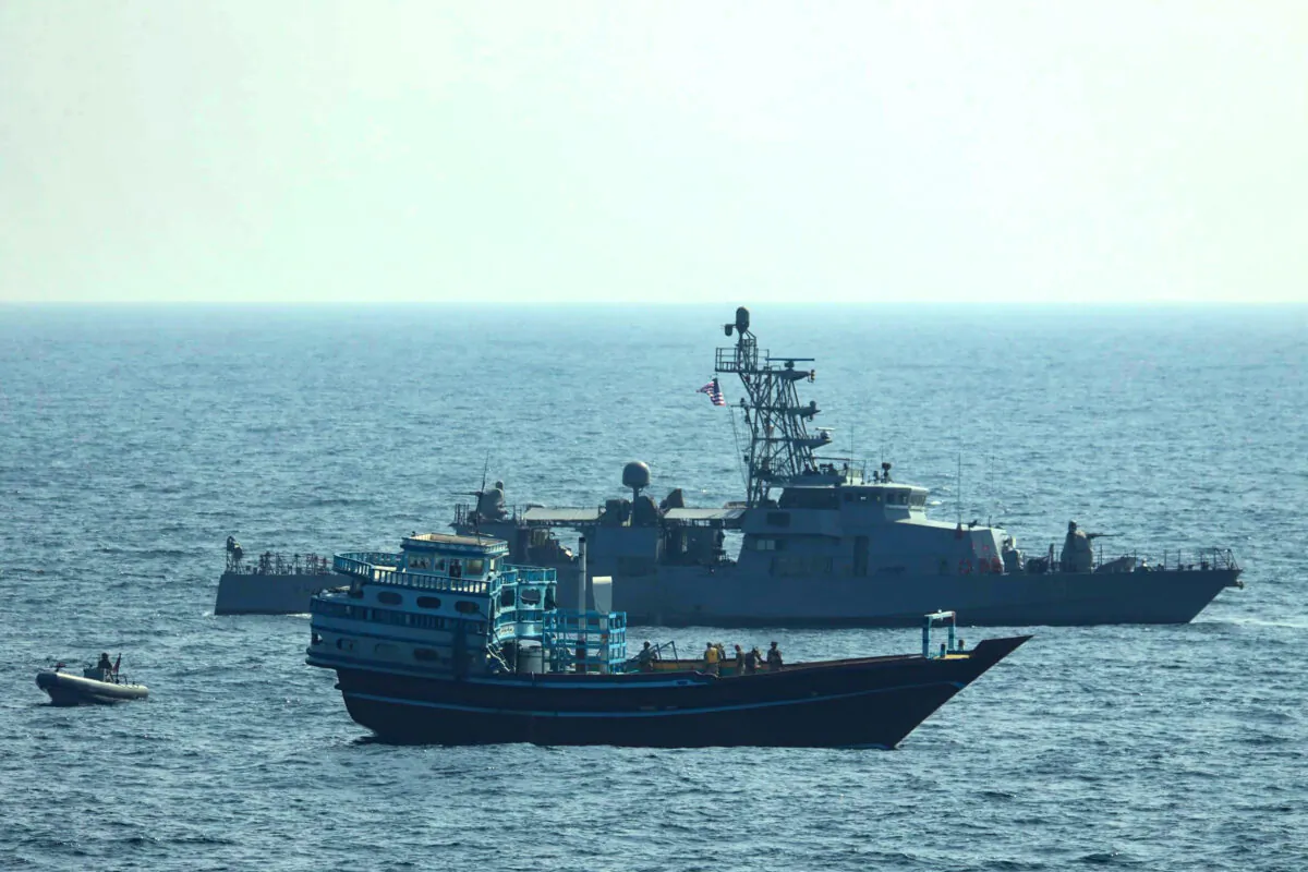 U.S. service members conduct a boarding on a stateless fishing vessel transiting international waters in the Gulf of Oman as a rigid-hull inflatable boat and patrol coastal ship USS Chinook (PC 9) sail nearby, on Jan. 18, 2022. (U.S. Navy via AP)