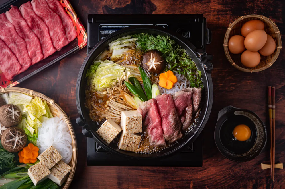 Sukiyaki is best shared, simmering away in the center of the table as diners huddle around to grab bites between warm conversation. (Atsushi Hirao/Shutterstock)