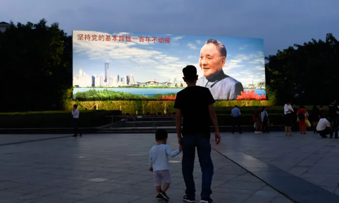 A man holds a boy's hand as they walk toward a poster of Chinese former leader Deng Xiaoping in Shenzhen in southern China's Guangdong province on Nov. 8, 2018. (Wang Zhao/AFP via Getty Images)