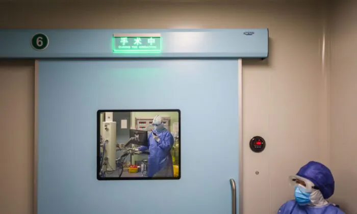 A medical staff member waits outside the operating room as doctors perform a caesarean section at a gynaecology and obstetrics isolation ward in Xiehe hospital in Wuhan, Hubei Province on March 7, 2020. (STR/AFP via Getty Images)