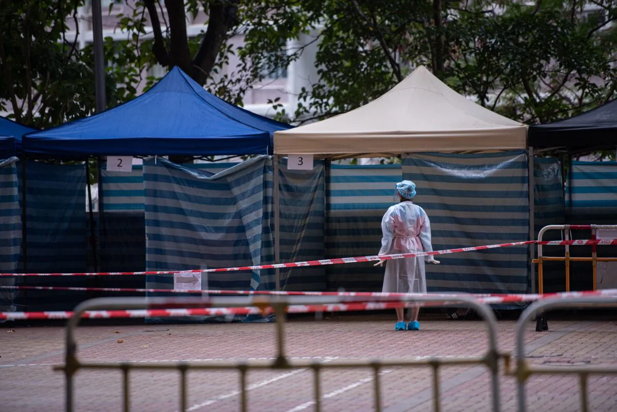 A health worker waits for residents to be screened for COVID-19 at a makeshift testing station outside a building placed under lockdown at the Kwai Chung Estate public housing complex in Hong Kong on Jan. 22, 2022. (Louise Delmotte/AFP via Getty Images)
