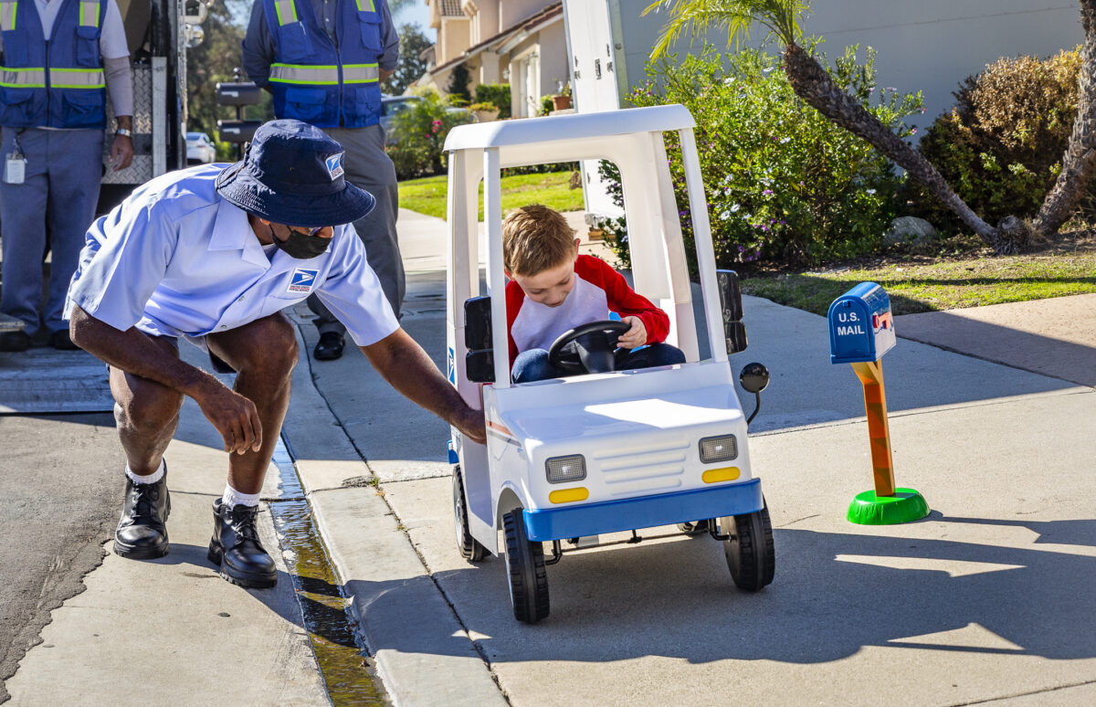 Seven-year-old Jacob Hayward receives gifts from his favorite mailman from the United States Postal Service, Van Singletary, at his home in Laguna Niguel, Calif., on Jan. 24, 2022. (John Fredricks/The Epoch Times)
