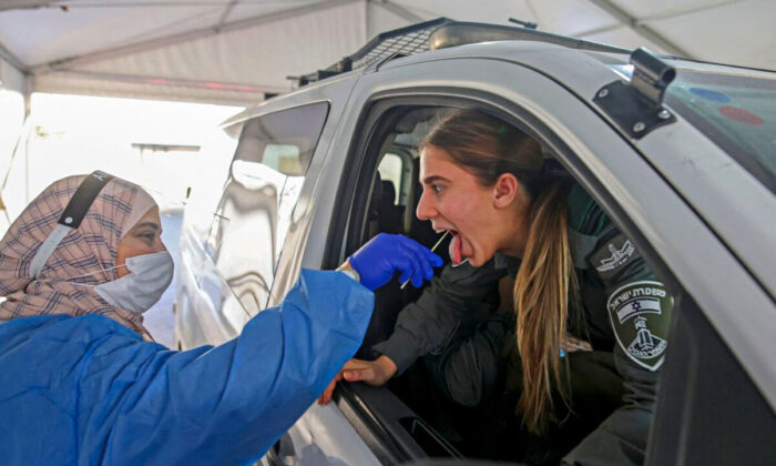 A medic collects a swab sample from an Israeli border guard at a COVID-19 drive-through testing site in a file photo. (Ahmad Gharabli/AFP via Getty Images)