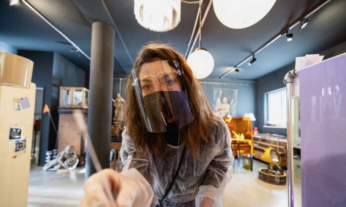 Judith Johanna Pawelke poses with a COVID-19 test in her interior design store, which is currently being used as a COVID-19 test station in downtown Munich, Germany, on Jan. 19, 2022. (Lukas Barth/Reuters)