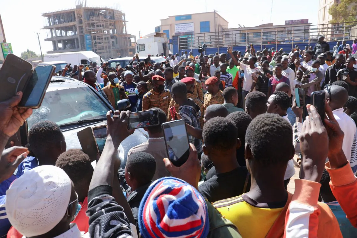 People gather around a vehicle belonging to the presidency, after Burkina Faso President Roch Kabore was detained at a military camp following heavy gunfire near the president's residence in Ouagadougou, Burkina Faso, on Jan. 24, 2022. (Vincent Bado/Reuters)