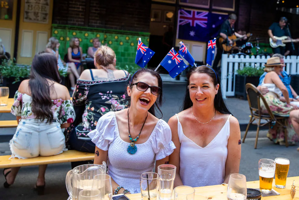 Women wearing Australian flags smile and look on at The Mercantile Hotel in The Rocks in Sydney, Australia, on Jan. 26, 2021. (Jenny Evans/Getty Images)