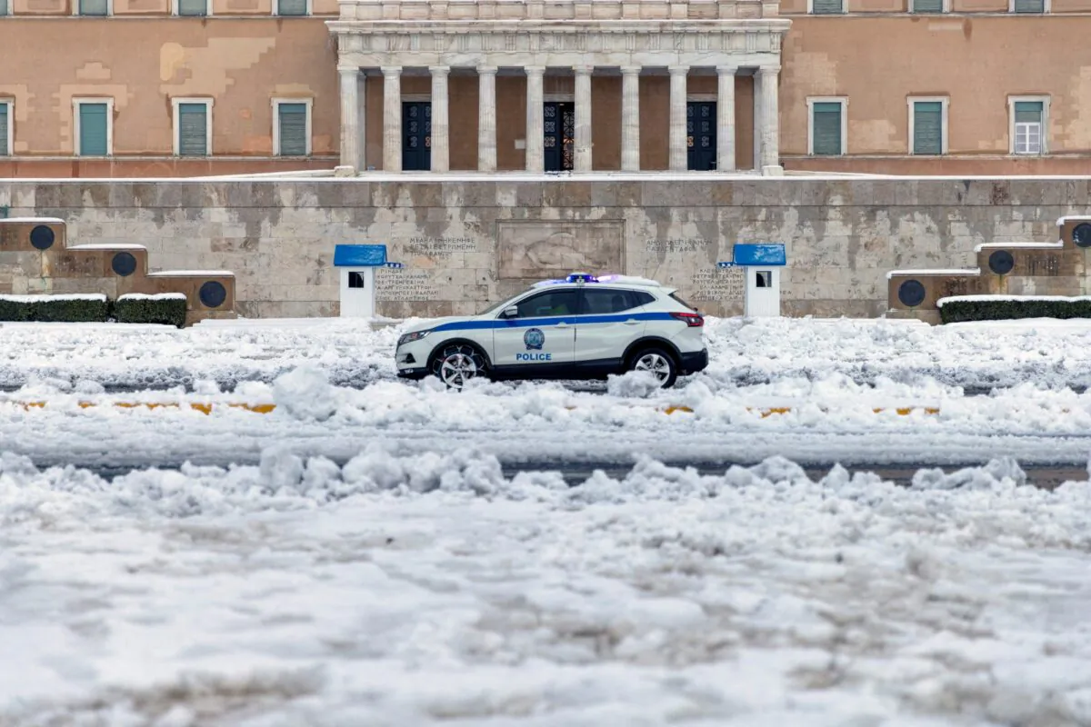 A police car drives past the Greek parliament building following heavy snowfall in Athens, Greece, on Jan. 25, 2022. (Alkis Konstantinidis/Reuters)