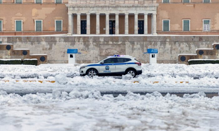 A police car drives past the Greek parliament building following heavy snowfall in Athens, Greece, on Jan. 25, 2022. (Alkis Konstantinidis/Reuters)