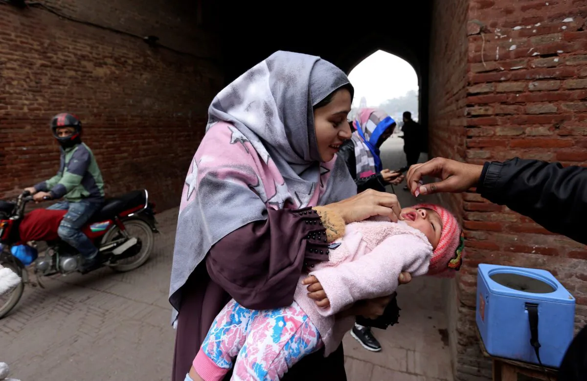 A health worker administers a polio vaccine to a child in a neighborhood of Lahore, Pakistan, on Jan. 25, 2022. (K.M. Chaudary/AP Photo)