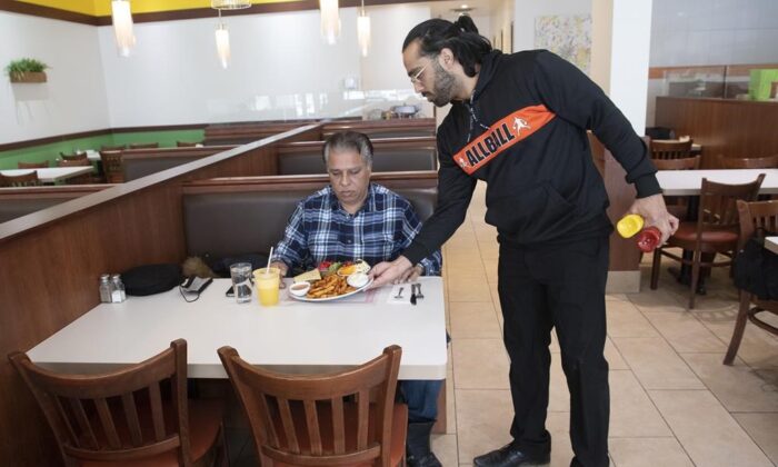 Humza Chaudhry, co-owner of Baba & Zazu, serves a customer at his restaurant in Montreal, on Jan. 25, 2022. (Graham Hughes/The Canadian Press)