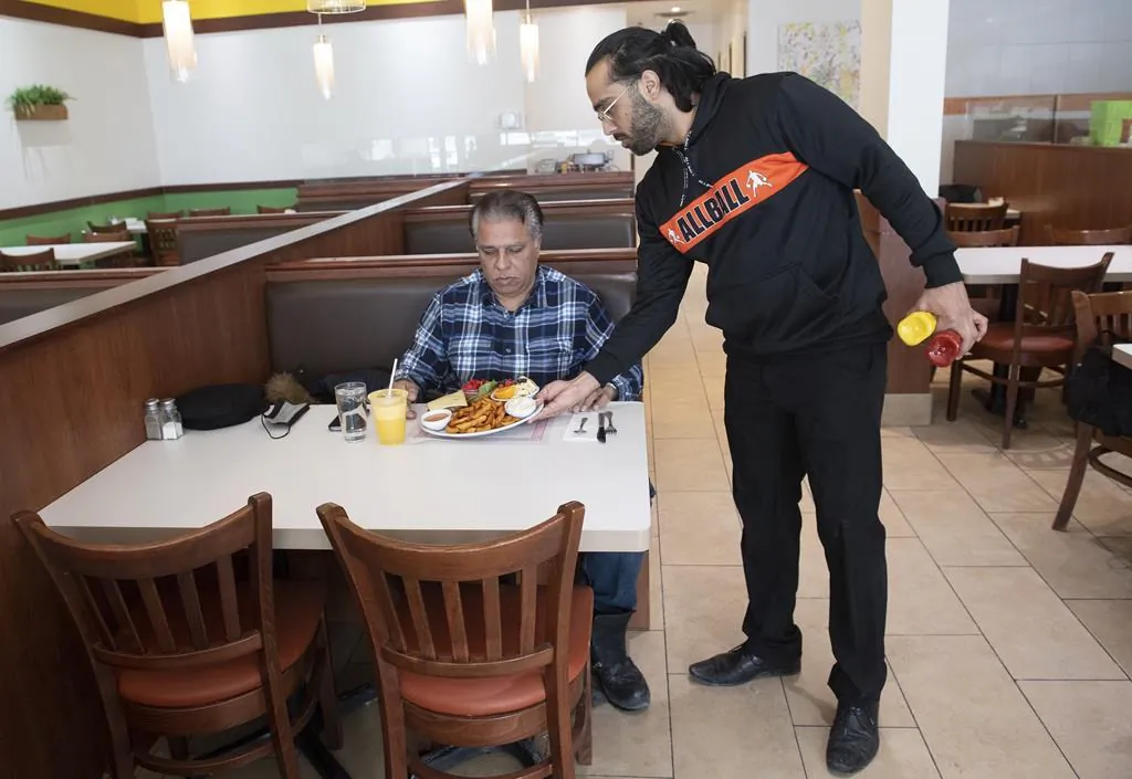 Humza Chaudhry, co-owner of Baba & Zazu, serves a customer at his restaurant in Montreal, on Jan. 25, 2022. (Graham Hughes/The Canadian Press)