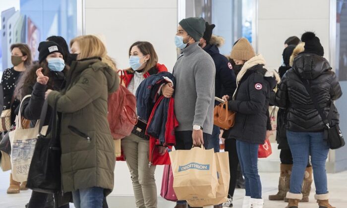 People wait in line to enter a clothing store in a shopping mall in Montreal, Jan. 15, 2022, as the COVID-19 pandemic continues in Canada. (The Canadian Press/Graham Hughes)