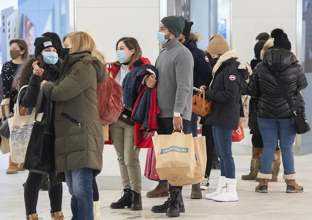 People wait in line to enter a clothing store in a shopping mall in Montreal, Jan. 15, 2022, as the COVID-19 pandemic continues in Canada. (The Canadian Press/Graham Hughes)